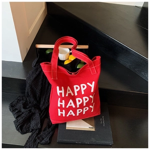 Detail of red canvas tote bag with bold white HAPPY HAPPY HAPPY typography on the front