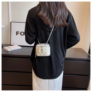Back view of a model wearing a white quilted mini vanity bag with a gold chain strap