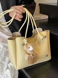 Pale yellow lychee grain leather tote bag with metal ball accents and cute bear pendant