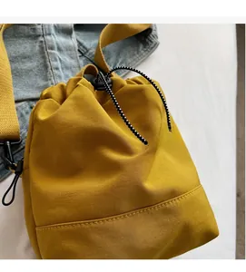 Detail of yellow drawstring bucket bag showing durable nylon fabric and woven cord strap