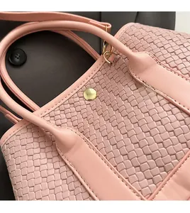 Close-up of pink woven handbag featuring detailed textures and elegant metal buckles