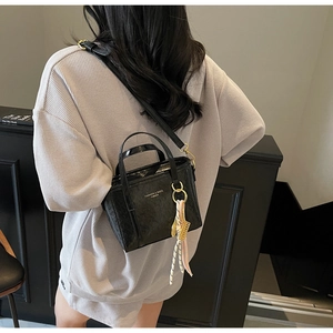 Fashionable black leather bucket bag with silk scarf charm and adjustable shoulder strap