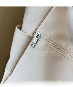 Detailed macro view of the smooth metal zipper and side pocket on the beige canvas tote bag