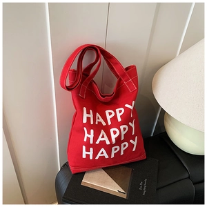 Detail of red canvas tote bag with white HAPPY print showing fine stitching and texture