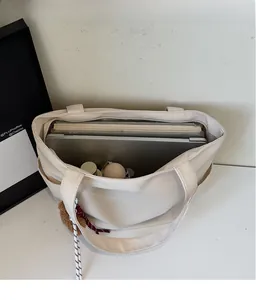 Detail view of the spacious inner compartment of the beige canvas tote bag with a laptop