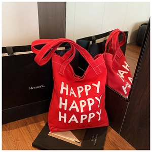 Detail of red canvas tote bag featuring white Happy lettering and neat stitching work