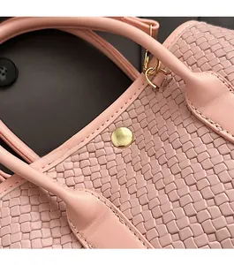 Close-up of pink woven texture bucket bag with gold snap button and leather handle