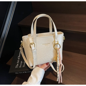 Macro view of white bucket bag featuring pebble leather texture and gold hardware details