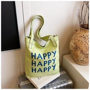 Detail of light green canvas tote bag featuring repeated blue Happy letter print