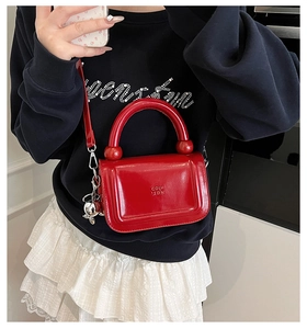 Détail du petit sac carré rouge brillant en cuir verni avec pendentif boule argentée