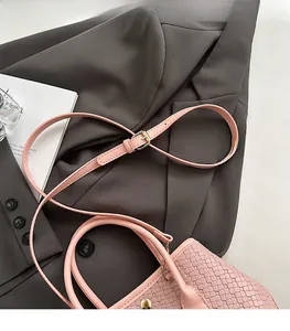 Detail of pink woven leather bag showing golden metal buckle and adjustable shoulder strap