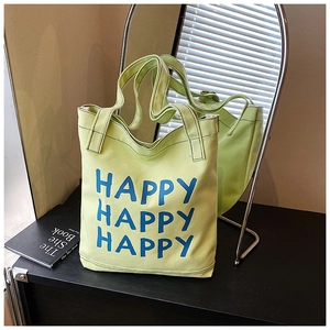 Close-up of light green canvas tote bag featuring blue Happy lettering on fabric