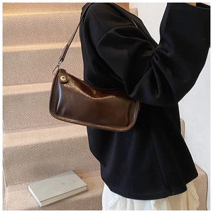 Détail du sac sous le bras vintage marron foncé en cuir brillant avec boucles dorées