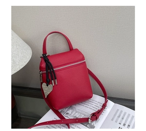 Détail du sac à main en cuir litchi rouge avec pendentif coeur argent et cordon noir chic