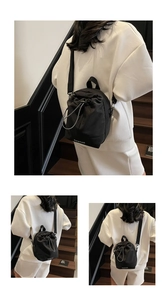 Detail of black drawstring nylon crossbody bag with COMTAO logo and adjustable strap