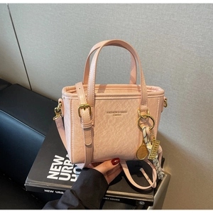 Close-up of pink bucket bag with lychee grain texture and golden tennis racket charm