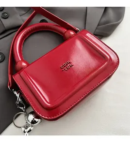 Détail du sac à main en cuir verni rouge avec pendentif chien argenté et logo gravé