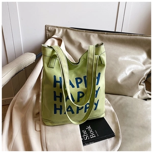 Detail of green canvas tote bag with large blue Happy Happy Happy letter print design