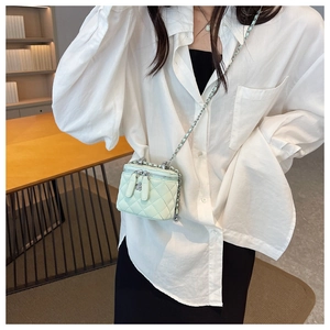Detailed view of mint green quilted mini chain bag with dual floral metal zippers