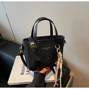 Close-up of black bucket bag with quilted texture and gold hardware detailing