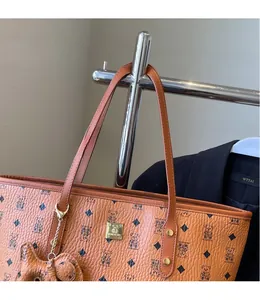 Detail of classic printed brown leather tote bag with bear pattern and metal charm