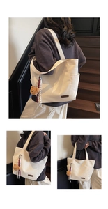 Detail view of off-white canvas tote bag featuring a leather patch and plush bear charm