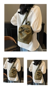 Detail of army green drawstring canvas bucket bag with adjustable straps and zipper pockets