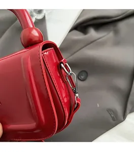 Détail du cuir ciré rouge brillant et de la boucle en métal argenté du sac à main