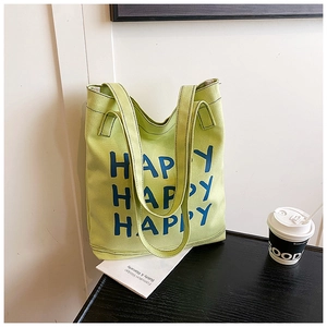 Detail of green canvas tote bag showing HAPPY print and sturdy shoulder straps