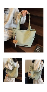 Detail of light green canvas tote bag with side pocket and cute brown bear pendant charm