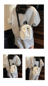 Detail view of white nylon drawstring bag showing the OOMTAO logo and adjustable strap