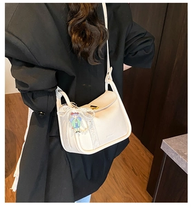 Detail view of cream white pillow shoulder bag with lace bow and cute charm