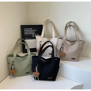 Detail view of large canvas tote bags in four colors with bear pendants and side pockets