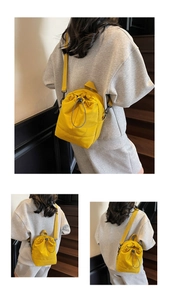 Detail of bright yellow drawstring crossbody bag with adjustable black strap and brand logo