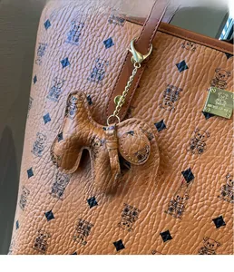 Close-up of brown pebbled leather tote bag with bear print and creative dog charm detail