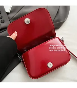 Détail du sac à bandoulière rouge brillant avec une fermeture magnétique double pratique