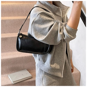 Détail du sac à bandoulière en cuir noir brillant avec boucle en métal argenté sur un mannequin