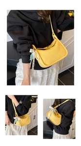 Detail of yellow crescent shoulder bag with lace bow, pearls, and leather texture