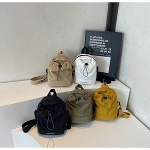 Multi-color nylon drawstring mini crossbody bags displayed on a minimalist white stand