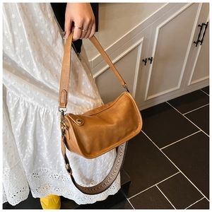 Détail du sac en cuir marron montrant la large bandoulière tissée et les ferrures dorées