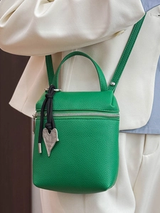 Petit sac carré vert avec texture litchi et pendentif coeur sur une tenue de blazer