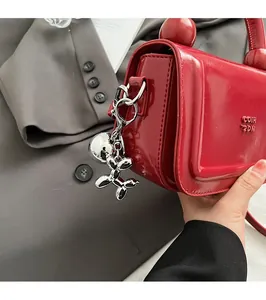 Détail d'un petit sac à main en cuir verni rouge avec pendentif chien ballon argenté