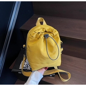 Detail of a bright yellow canvas drawstring crossbody bag with black plastic cord lock