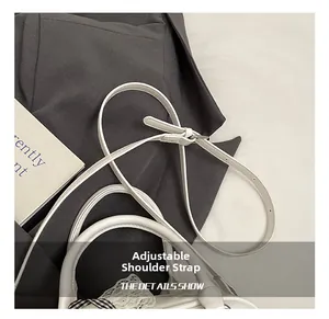 Detail view of white leather adjustable shoulder strap with metal buckle for underarm bag