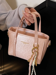Minimalist light pink bucket bag with metallic crinkle finish and woven strap accessory