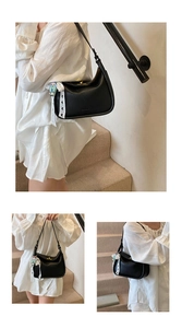 Detail of black lychee leather shoulder bag with lace ribbon and elegant charms