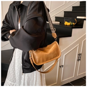 Détail du sac sous le bras en cuir caramel avec une large bandoulière jacquard vintage