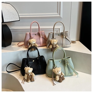 Detail view of woven texture handbags in pink beige black and green with bear charms