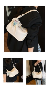 Detail of white litchi pattern leather shoulder bag with gold clasp and lace bow charm