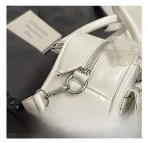 Detailed macro view of white pleated leather bag with silver metal hooks and lace details